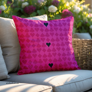 Pink pillow with black heart pattern on a beige couch outdoors