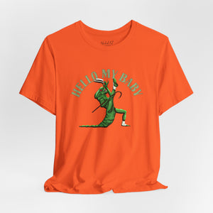 An orange short-sleeve crewneck t-shirt featuring a green alien dancing, with the text 'HELLO MY BABY' arched above it, displayed on a light gray background.