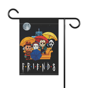 A decorative garden flag hanging from a black metal stand against a white background. The flag features illustrated characters from 80's horror under colorful umbrellas on a black night-sky background with a moon and couch, and the word 'FRIENDS' at the bottom.