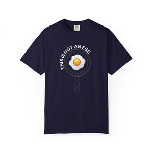 A navy blue short-sleeve t-shirt with a graphic of a fried egg inside a frying pan, with the text 'THIS IS NOT AN EGG' arched above it, displayed on a clean white background.