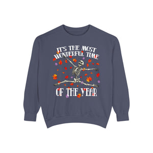 A navy blue crewneck sweatshirt featuring a Halloween graphic of a dancing skeleton surrounded by falling red and orange leaves, with the text 'IT'S THE MOST WONDERFUL TIME OF THE YEAR'.