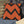 Orange and black zigzag patterned pillow on a gray cushion with a straw hat nearby.