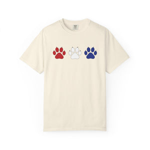 Beige t-shirt with red, white, and blue paw prints on a white background