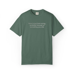 Blue Green t-shirt with 'Rain is just God crying, probably because of something  you did." embroidered text on a white background