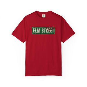 A red short-sleeve crewneck t-shirt featuring a distressed green 'ELM STREET' sign graphic on the chest, displayed against a solid white background.