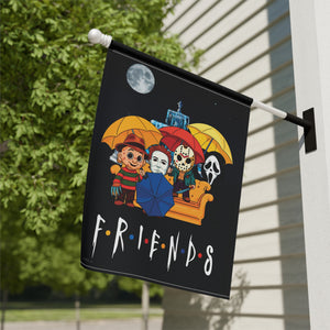 A black decorative flag hanging from a white pole on a house exterior, featuring cartoon characters under yellow and blue umbrellas above the word “FRIENDS” in the Friends from The Simpsons style. Trees and siding are visible in the background.