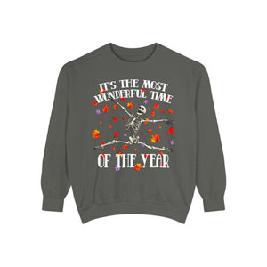 A dark gray crewneck sweatshirt featuring a Halloween graphic of a dancing skeleton surrounded by red and orange autumn leaves, with white text that reads 'IT'S THE MOST WONDERFUL TIME OF THE YEAR'.