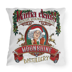 A square white throw pillow featuring a festive graphic print of 'Mama Claus' Moonshine Distillery. The design includes a Christmas tree, holly, reindeer, and an illustration of an elderly woman in a Santa hat holding moonshine bottles.