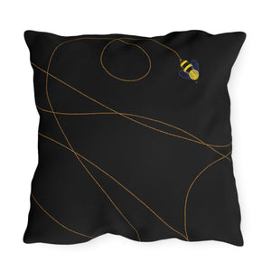 A black outdoor throw pillow with a geometric pattern and a small bee design in a corner.