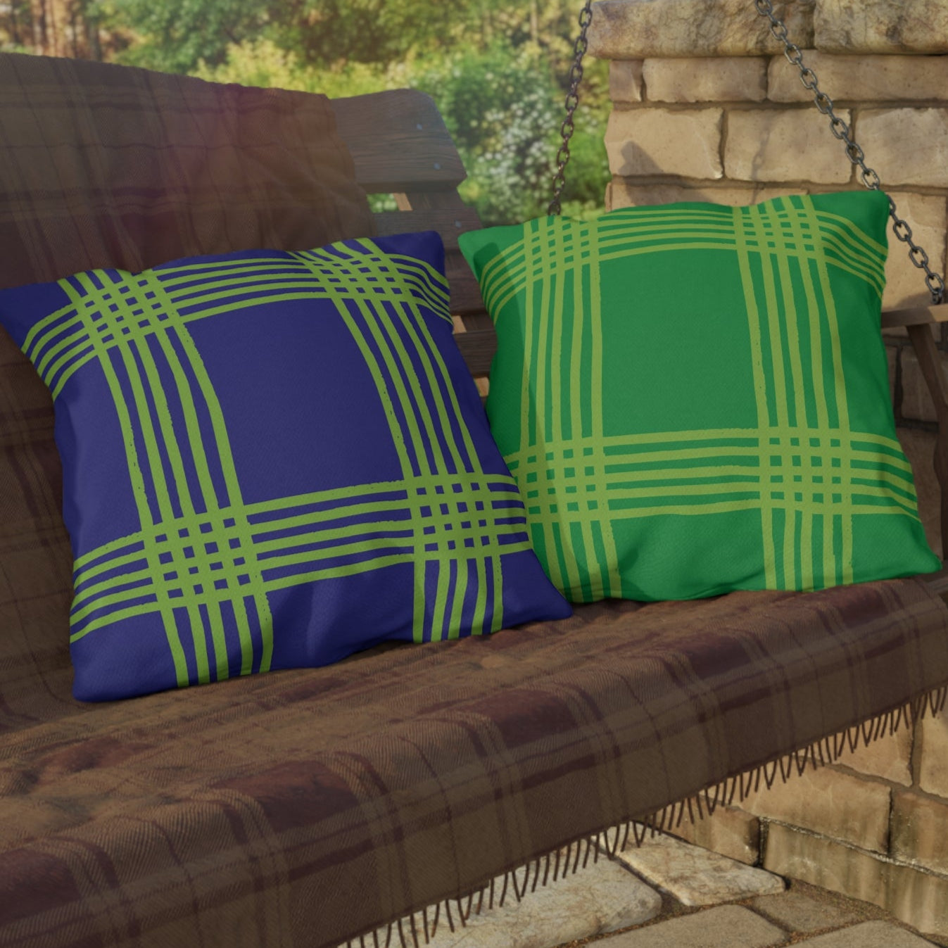 Wooden swing with plaid blue purple and green cushions on a stone porch.