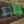 Wooden swing with plaid blue purple and green cushions on a stone porch.