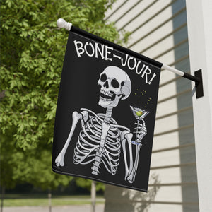 Yard flag and banner with a skeleton holding a martini that says Bone-jour at the top on a black background.