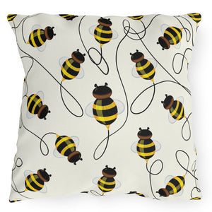 A square-shaped accent pillow with a pattern of colorful bees against a white background.