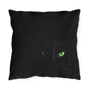A square black throw pillow featuring a printed graphic of a black cat with bright green eyes, shown against a plain white background.