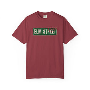 A maroon short-sleeve crewneck t-shirt featuring a distressed green 'ELM STREET' sign graphic on the chest, displayed against a plain white background.