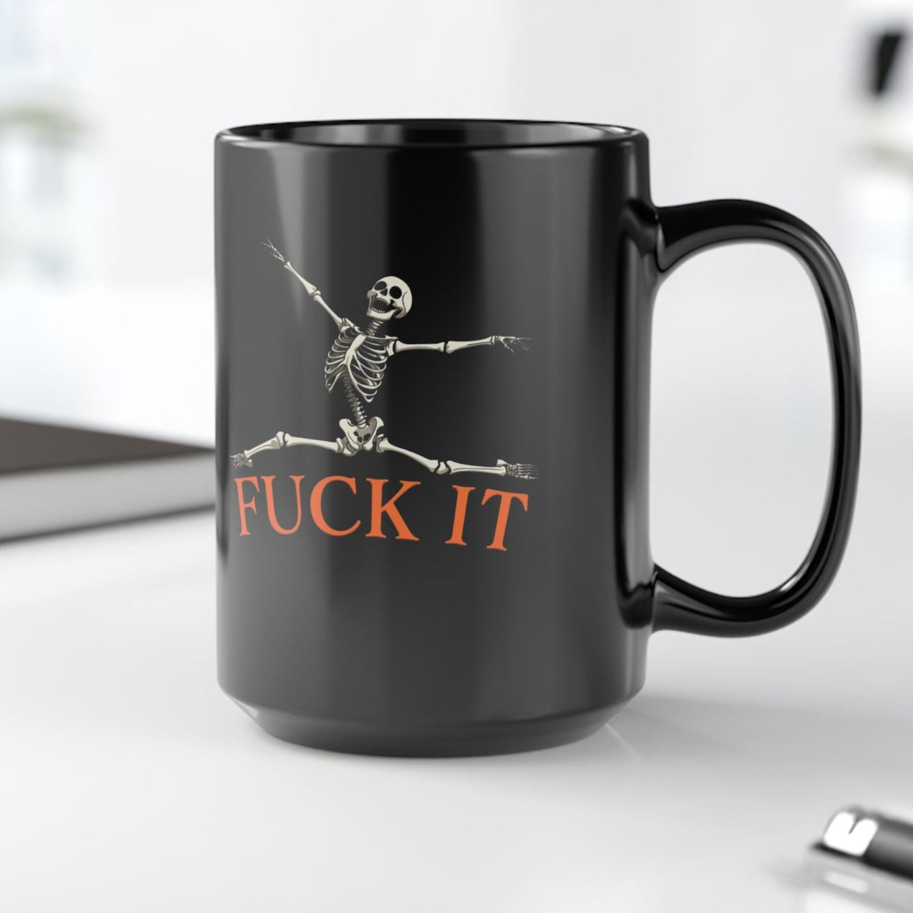 Black mug with skeleton design and 'FUCK IT' text on a white background