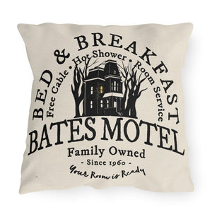 A beige throw pillow with a black and gray print of the Bates Motel sign, text detailing the motel's services, and a graphic of a house. The words 'Bed & Breakfast' are also printed on the pillow.