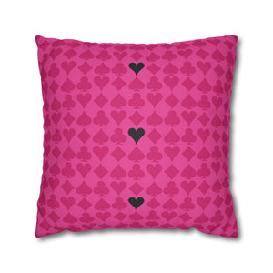 A square-shaped accent pillow with a pink background featuring a repeated pattern of black hearts, resembling a deck of cards.