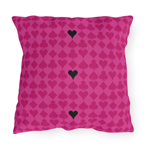 A square-shaped throw pillow with a pink background featuring a repeated pattern of black playing card hearts.