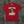 Red t-shirt with graphic design and text on a wooden surface