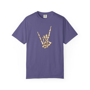 A purple short-sleeve crewneck t-shirt featuring a graphic of a skeletal hand making the rock on gesture on the chest, displayed against a solid white background.