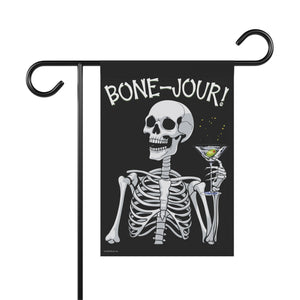 Yard flag and banner with a skeleton holding a martini that says Bone-jour at the top on a black background.