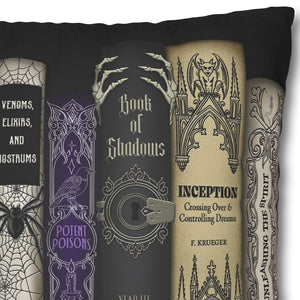 A square black throw pillow featuring a printed graphic of book spines in a gothic style, including titles like 'The Glass Cauldron', 'Venoms, Elixirs, and Nootrums', 'Book of Shadows', and 'Inception'.