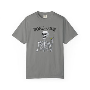 Grey t-shirt with a graphic of a skeleton holding a martini with Bone-Jour in bone style lettering at the top.