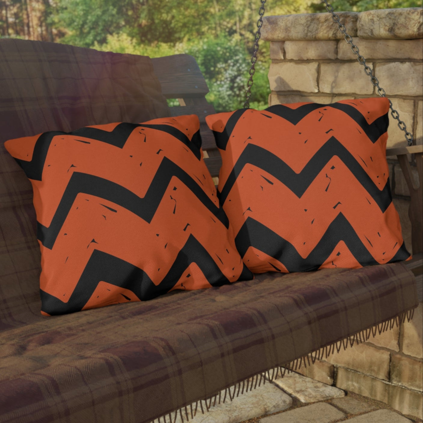 Outdoor swing with orange and black chevron cushions on a stone patio.