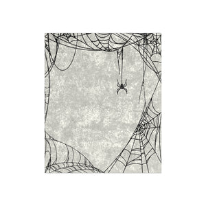 A decorative throw blanket featuring a black spider and intricate spiderwebs centered on a solid white backdrop.