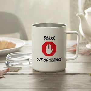 White mug with 'Sorry, Out of Service' design on a wooden table with a teapot and bread in the background.