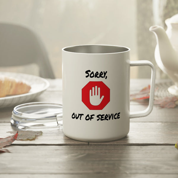 White mug with 'Sorry, Out of Service' design on a wooden table with a teapot and bread in the background.