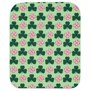 A rectangular baby blanket with a green background and a pattern of pink and green shamrocks.