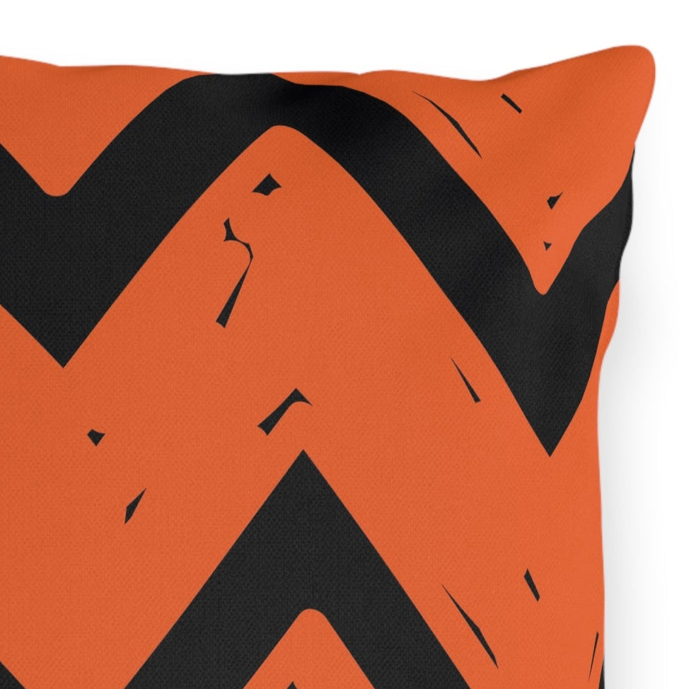 Orange pillow with black zigzag pattern on a white background