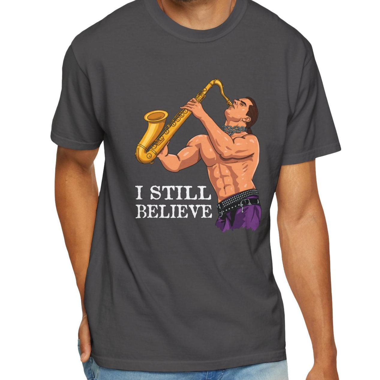Man wearing a dark gray t-shirt with a graphic of a man playing saxophone and text 'I STILL BELIEVE' on a white background.