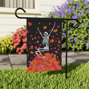 Garden flag with skeleton design on a stand in front of flowers