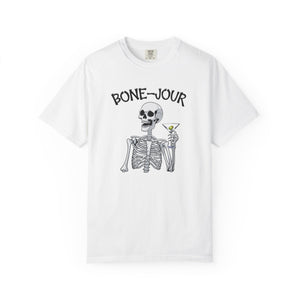 White t-shirt with a graphic of a skeleton holding a martini with Bone-Jour in bone style lettering at the top.