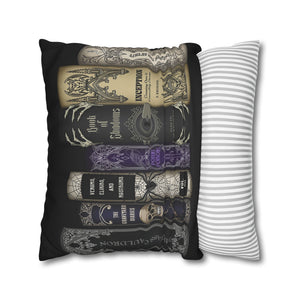 A rectangular throw pillow with a black background and a graphic print of vintage occult book spines in beige, gray, and purple, shown next to a white pillow with thin gray stripes on a white background.