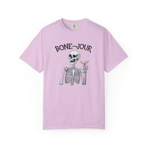 Light purple t-shirt with a graphic of a skeleton holding a martini with Bone-Jour in bone style lettering at the top.