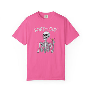 Bright pink t-shirt with a graphic of a skeleton holding a martini with Bone-Jour in bone style lettering at the top.