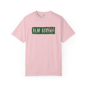 A light pink short-sleeve crewneck t-shirt featuring a distressed green 'ELM STREET' sign graphic printed across the chest.