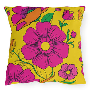 A square-shaped accent pillow with a vibrant yellow background and bold pink floral pattern, featuring green leaves and stems.