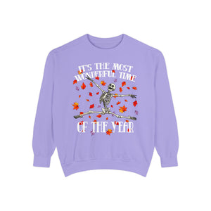 A lavender crewneck sweatshirt featuring a skeleton dancing amidst red and orange autumn leaves, with the text 'IT'S THE MOST WONDERFUL TIME OF THE YEAR' printed in white.