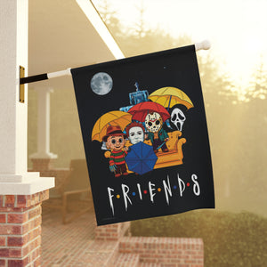 A black decorative garden flag hanging from a porch eave. The flag features a colorful cartoon illustration of 80's horror characters with umbrellas on a couch, a moon, and the word 'FRIENDS' in a distressed white font.