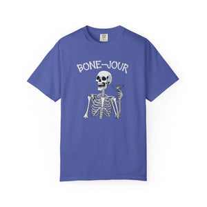 Periwinkle t-shirt with a graphic of a skeleton holding a martini with Bone-Jour in bone style lettering at the top.