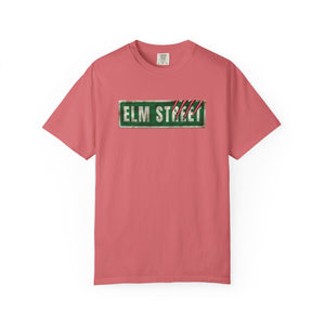A pink short-sleeve crewneck t-shirt featuring a distressed green 'ELM STREET' sign graphic printed across the chest.