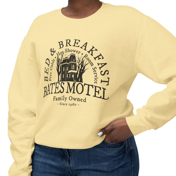 Woman wearing a yellow sweatshirt with 'Bates Motel' graphic design on a white background