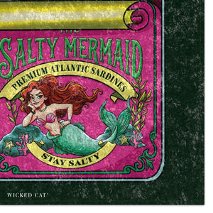 A close-up of a product label or package design featuring an illustrated mermaid with red hair and a green tail on a pink background, with text reading 'The Salty Mermaid' and 'Stay Salty.' The product itself is partially visible against a dark textured background, and the brand name 'Wicked Cat' appears at the bottom left.