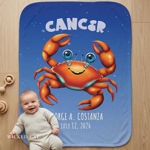 Baby sitting on a blue blanket with a cartoon crab and personalized text on a wooden floor.