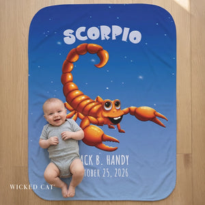 Baby lying on a blanket with a cartoon scorpion and personalized text on a wooden surface
